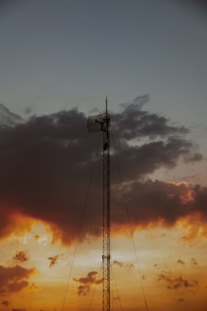 A tall communication tower silhouetted against a vibrant, dramatic sunset sky.