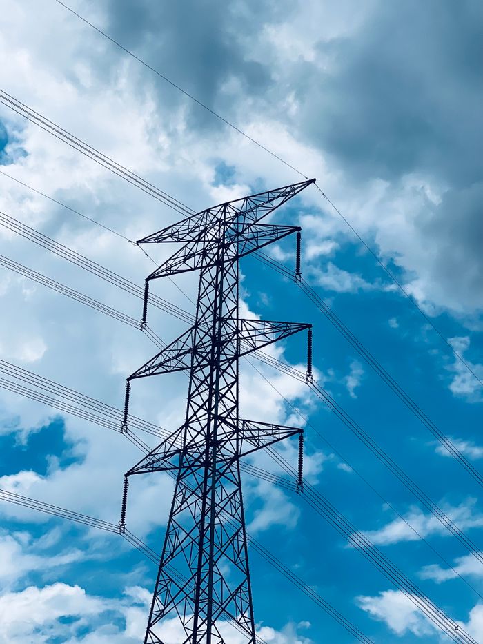 Steel transmission tower against a dramatic cloudy blue sky.
