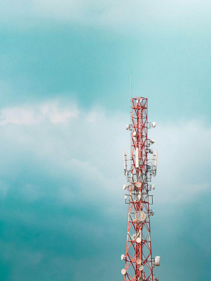 A red radio tower stands tall against a clear blue sky, showcasing modern telecommunications.