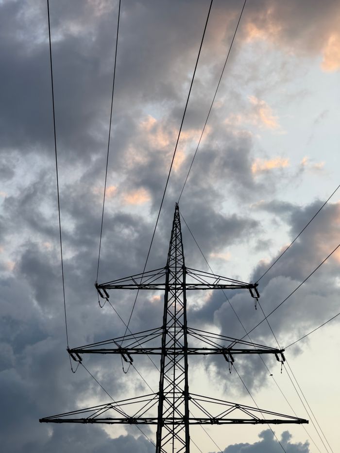 Home High tension power lines against a dramatic cloudy sky at dusk.