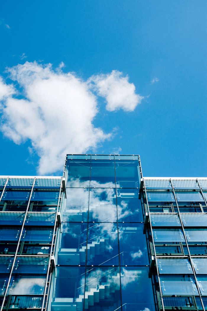 Home From below exterior of modern multistorey office building beneath cloudless blue sky in city center