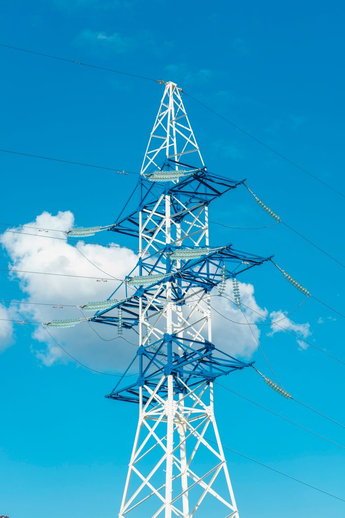 A tall electricity transmission tower with wires against a clear blue sky.
